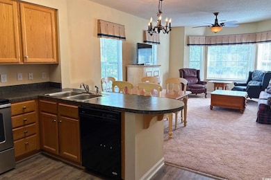 Kitchen with open floor plan, dark countertops, black dishwasher, a peninsula, and pendant lighting