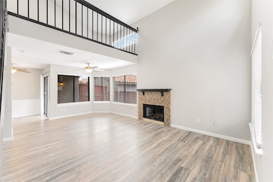 Unfurnished living room featuring a towering ceiling, a fireplace, and light wood-type flooring