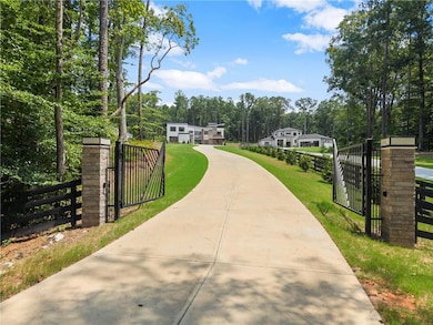 View of home's community with concrete driveway, a gate, and view of wooded area