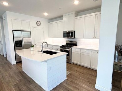 Kitchen with white cabinetry, dark hardwood / wood