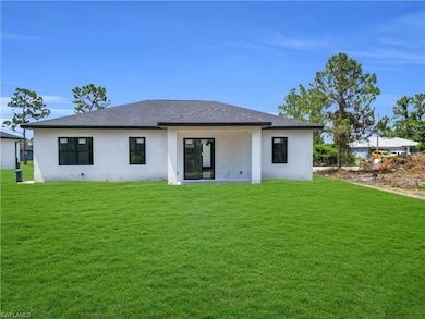 Back of house with stucco siding, a yard, and roof with shingles