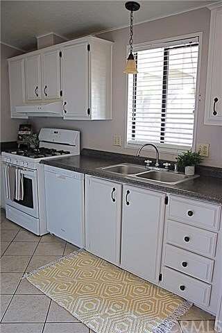 Cheery white kitchen with stainless sink, gas stov