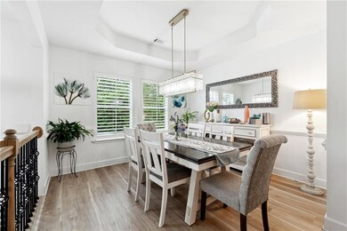 Dining space featuring a raised ceiling, wood finished floors, and baseboards