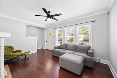 Living room featuring ceiling fan, dark hardwood / wood-style flooring, and ornamental molding