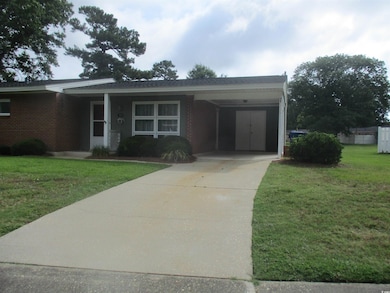 View of front facade with a carport and a front lawn