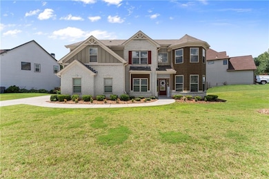 View of front of property with board and batten siding, brick siding, and a front lawn