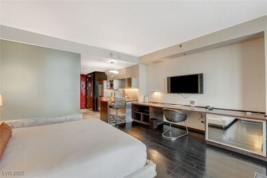 Bedroom with wood finished floors and an office ar