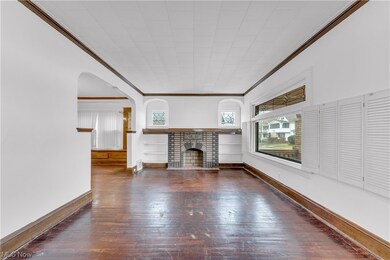 Unfurnished living room featuring dark hardwood / wood-style flooring, a brick fireplace, and ornamental molding