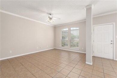 Tiled spare room with ceiling fan and crown moldin