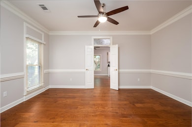Dining room featuring healthy amount of natural light, ceiling fan, crown molding, wood finished floors, and baseboards