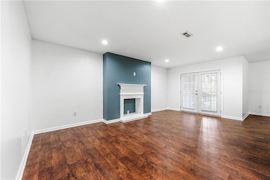 Unfurnished living room featuring baseboards, dark wood-style flooring, recessed lighting, and a glass covered fireplace
