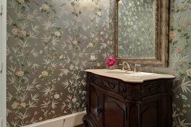Powder room off entry hall complete with custom wall coverings, antique mirror and bath vanity with marble top.