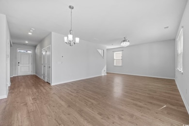 Unfurnished living room with a chandelier and light wood-style floors