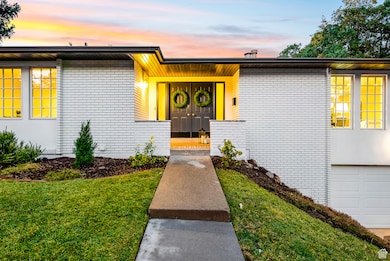 Mid-century inspired home with brick siding, a yard, and an attached garage