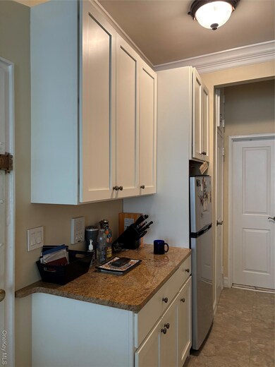 Kitchen featuring white cabinets, refrigerator, and dark stone countertops