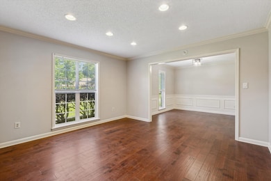 Spare room featuring a textured ceiling, dark wood finished floors, crown molding, and recessed lighting