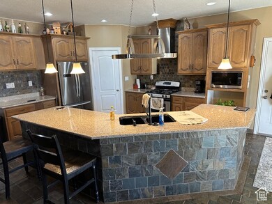 Kitchen featuring backsplash, appliances with stainless steel finishes, a kitchen bar, sink, and a spacious island