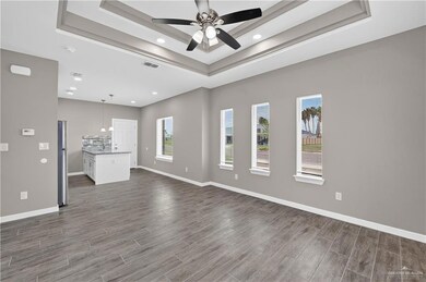 Unfurnished living room featuring a raised ceiling, ceiling fan, dark wood-type flooring, and recessed lighting