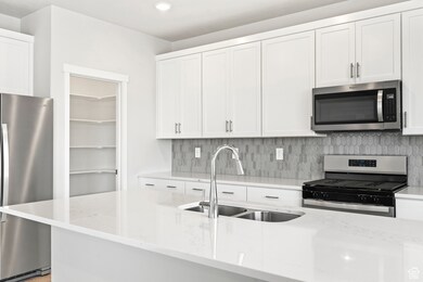 Kitchen featuring backsplash, stainless steel appliances, light stone counters, and a sink