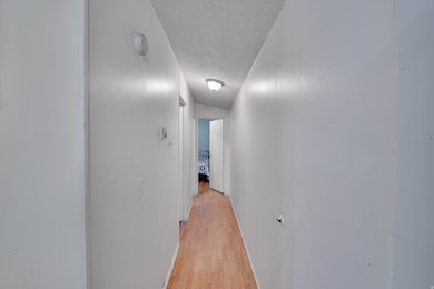 Corridor featuring a textured ceiling and light wood-style floors