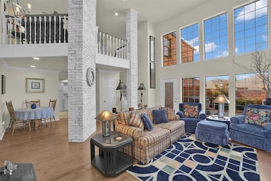 Living area with ornate columns, wood finished floors, a towering ceiling, recessed lighting, and ornamental molding