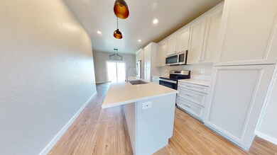 Kitchen with a kitchen island with sink, hanging light fixtures, light wood-style flooring, stainless steel appliances, and recessed lighting