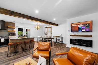 Living area featuring beamed ceiling, baseboards, 