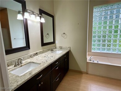 Bathroom featuring double vanity, a bath, and light wood finished floors