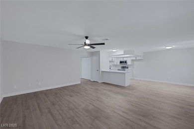 Unfurnished living room featuring a ceiling fan, b