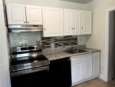 Kitchen with stainless steel range with electric cooktop, under cabinet range hood, a sink, and backsplash