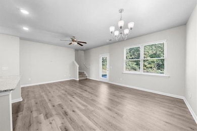 Unfurnished living room featuring stairs, light wood-style flooring, baseboards, recessed lighting, and a chandelier