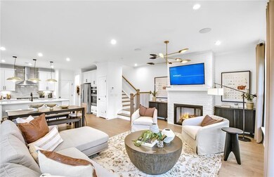 Living area featuring stairway, light wood finished floors, a brick fireplace, a chandelier, and recessed lighting