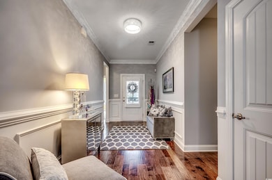 Entrance foyer with dark wood-type flooring and crown molding