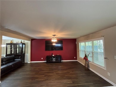 Unfurnished living room featuring dark wood-style floors and ceiling fan