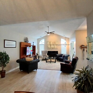 Living room featuring ceiling fan, vaulted ceiling