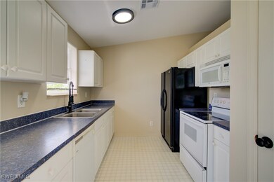 Kitchen with white appliances, a sink, dark counte