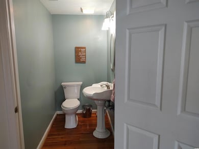 Bathroom with wood finished floors, toilet, basebo
