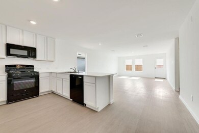 Kitchen featuring black appliances, a peninsula, light wood finished floors, open floor plan, and recessed lighting