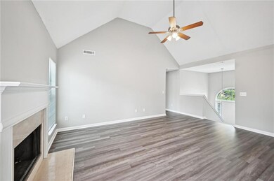 Unfurnished living room featuring high vaulted ceiling, a ceiling fan, wood finished floors, a fireplace, and baseboards