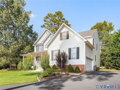 Traditional-style home with covered porch, asphalt driveway, and a front yard