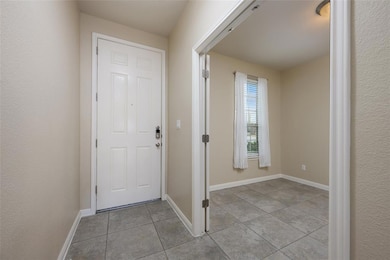 Entryway with light tile patterned flooring and a textured wall