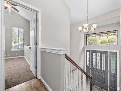 Foyer entrance with wood finished floors, vaulted ceiling, and a chandelier