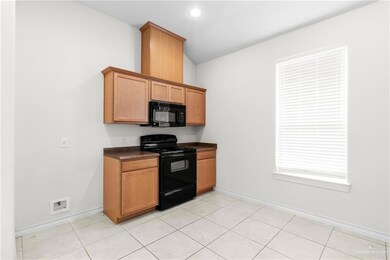 Kitchen featuring vaulted ceiling, light tile patterned floors, and black appliances