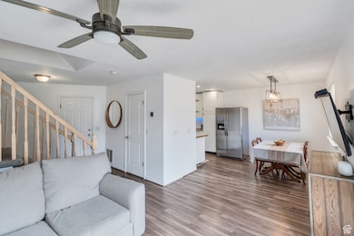 Living area featuring wood finished floors, ceiling fan, and stairway