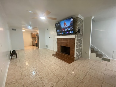 Unfurnished living room featuring light tile patterned floors, a fireplace, ceiling fan, and stairs