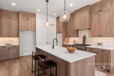Kitchen with tasteful backsplash, light wood-type flooring, light countertops, hanging light fixtures, and recessed lighting
