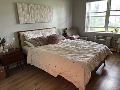 Bedroom with hardwood / wood-style flooring and an AC wall unit
