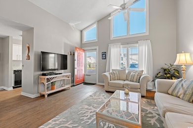 Living area featuring a towering ceiling, wood-type flooring, and a ceiling fan