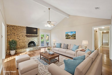 STAGED photo Living room featuring beam ceiling, a brick fireplace, hardwood / wood-style flooring, a ceiling fan, and high vaulted ceiling