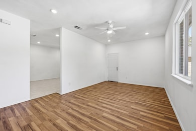 Large living room featuring light wood-type flooring, recessed lighting, and ceiling fan